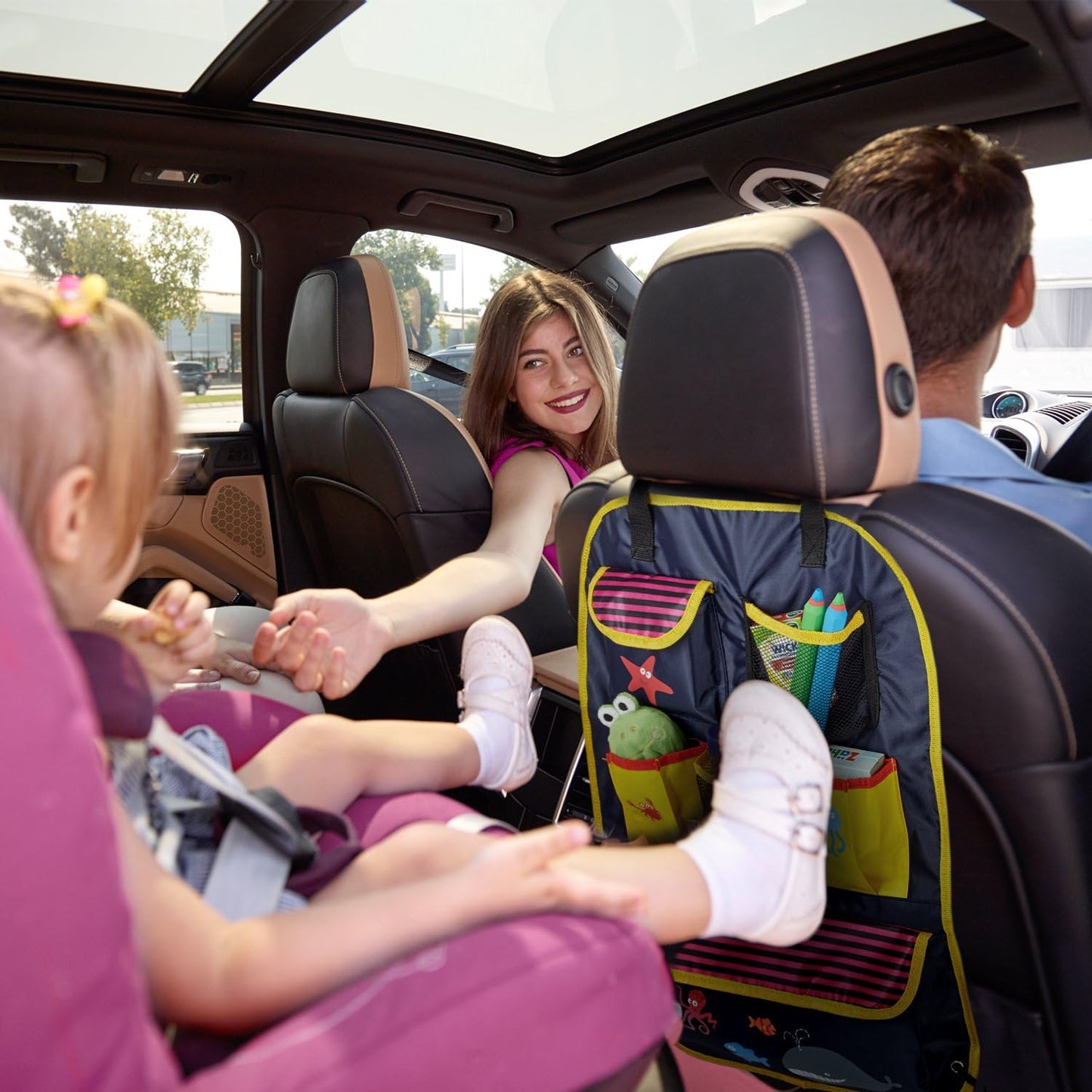 family in a car with bright back seat organiser storing toys and tablet in car